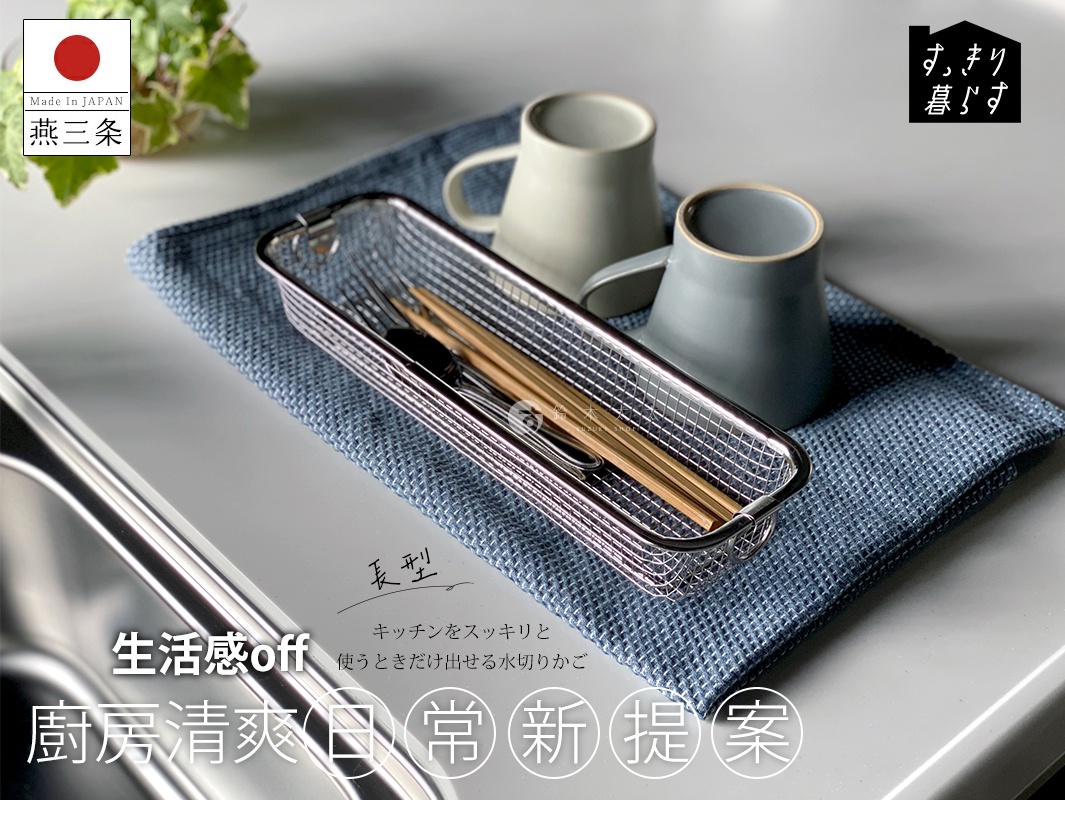 不鏽鋼長型簡約瀝水籃，網格狀設計，內部放置著筷子、湯匙和叉子。一旁有兩個馬克杯，一個為淺灰色，另一個為藍灰色，置於藍色格紋布上。