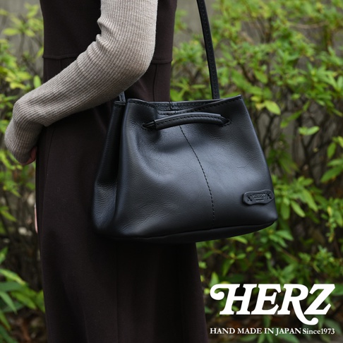 HERZ 職人手作黑色皮革束口兩用包，包款上有品牌標誌，下方有 HAND MADE IN JAPAN Since1973 字樣