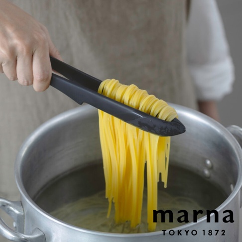 marna TOKYO 1872 黑色食物夾夾著烹煮中的義大利麵，下方為鍋子。