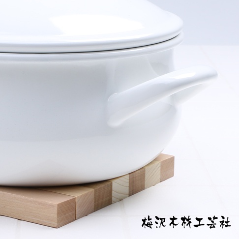 木製翻轉隔熱墊，由多塊淺棕色木塊拼接而成，質樸自然。隔熱墊下方放置一個白色帶有雙耳的鍋具。