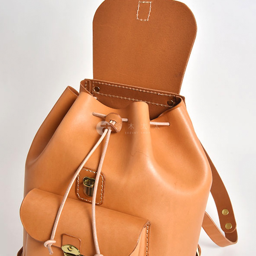 一個棕褐色皮革後背包，頂部翻蓋打開，露出抽繩開口和兩個前置口袋。