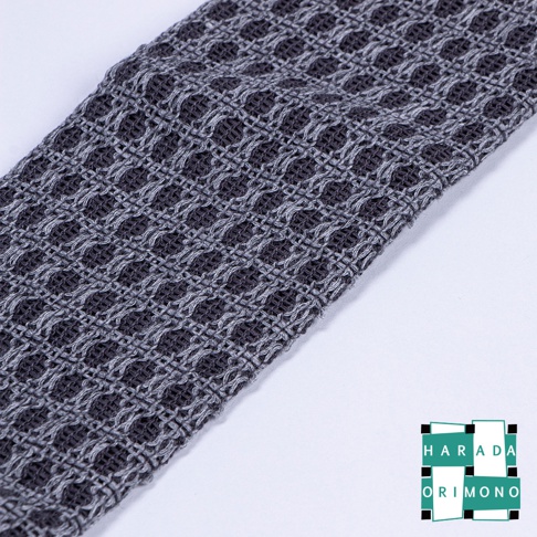 深灰色紋理沐浴巾，採用網格編織，觸感蓬鬆。