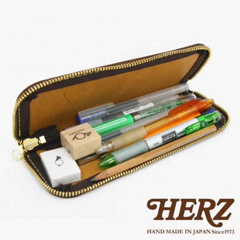 一個棕色皮革製的筆袋，裡面裝有多種筆，包括鋼筆、原子筆和鉛筆，以及一個小橡皮擦和一個木製印章。