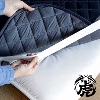 兩隻手正將深灰色菱格紋的竹炭床墊套在白色床墊上，床墊邊緣有白色固定綁帶。