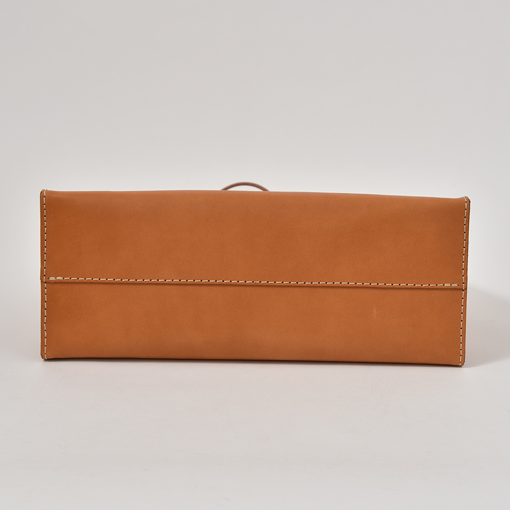 職人手作皮革提袋 T-5，採用棕褐色皮革製成，袋身結構方正，縫線整齊，展現簡約設計。