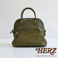 橄欖綠皮革手提包，經典貝殼造型，設有頂部提把、金色拉鍊前袋與側邊掛環。