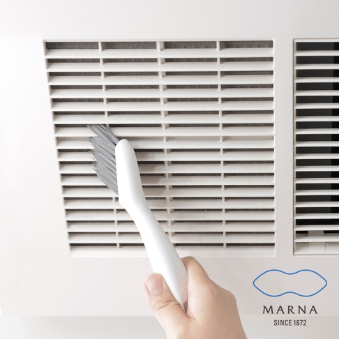 白色手柄的縫隙清潔刷，其灰色刷毛正清潔著白色格柵狀的表面。