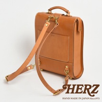 職人手作皮革杜勒斯商務後背包，淺棕色皮革製成，帶有可調節的皮革肩帶和金屬扣環。包身方形，有縫線細節和一個外層口袋，上印有品牌標誌。