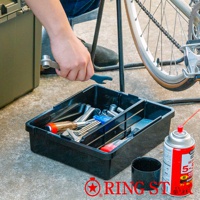 黑色塑膠工具箱內有各式扳手、螺絲起子和藍色零件，箱子旁有一罐紅色噴霧罐和一個黑色杯子。