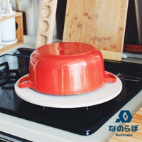 圓形珪藻土置物墊，白色底搭配細緻的灰色條紋，上方放置一個紅色圓形鑄鐵鍋。