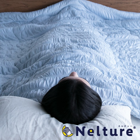 淺藍色單人被，表面有細緻的壓紋，覆蓋著一位躺在枕頭上的人。