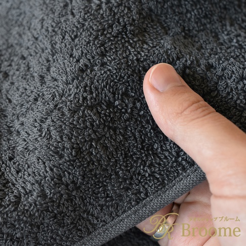 特寫展示灰色純棉毛巾的細膩柔軟織紋，手指觸碰毛巾材質，展現其蓬鬆觸感。