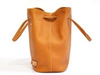 職人手作皮革可調式兩用大容量托特包，為棕褐色牛皮材質，束口設計，附有兩條可調整皮革提把，包體側面有縫線裝飾，底部有一個皮革製的固定扣。