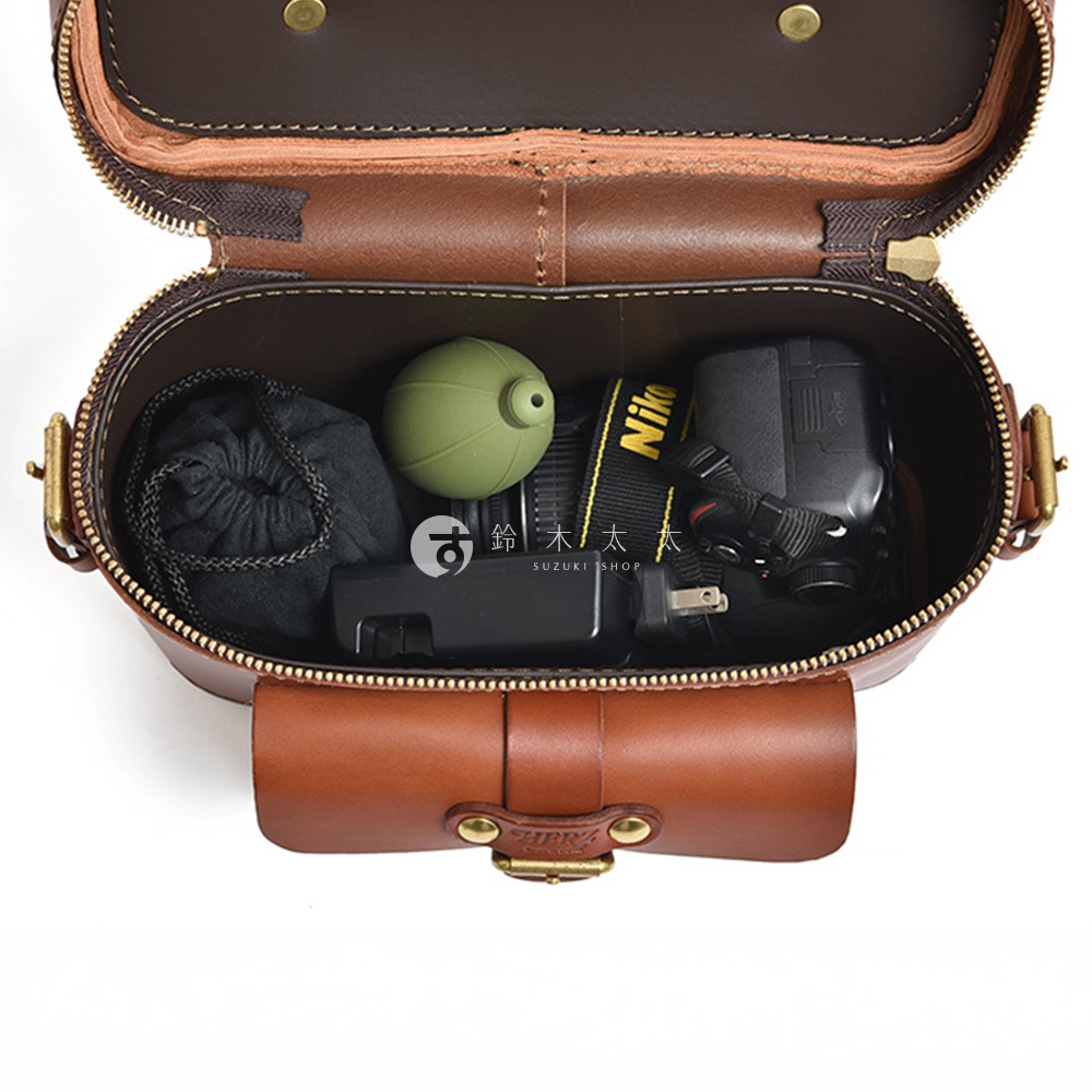 日本HERZ職人手作皮革相機包，內部裝有相機、鏡頭、綠色圓形小物及黑色收納袋。