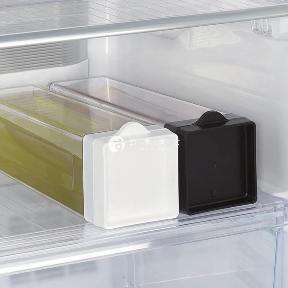 冰箱內兩個長方形透明冷水壺，分別有白色和黑色瓶蓋，其中一個裝有淡黃色液體，旁邊標有「SUZUKI SHOP」字樣。