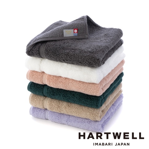 一疊六色今治毛巾，包含深灰、純白、淺粉、墨綠、米褐與淡紫，毛巾表面呈現細緻絨毛質感。