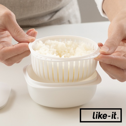 簡約雙層蒸氣循環保鮮盒，白色塑膠材質，上層為帶有蒸氣孔的濾網碗，內盛白米飯，下層為儲水盒，雙手正將濾網碗置入盒中。