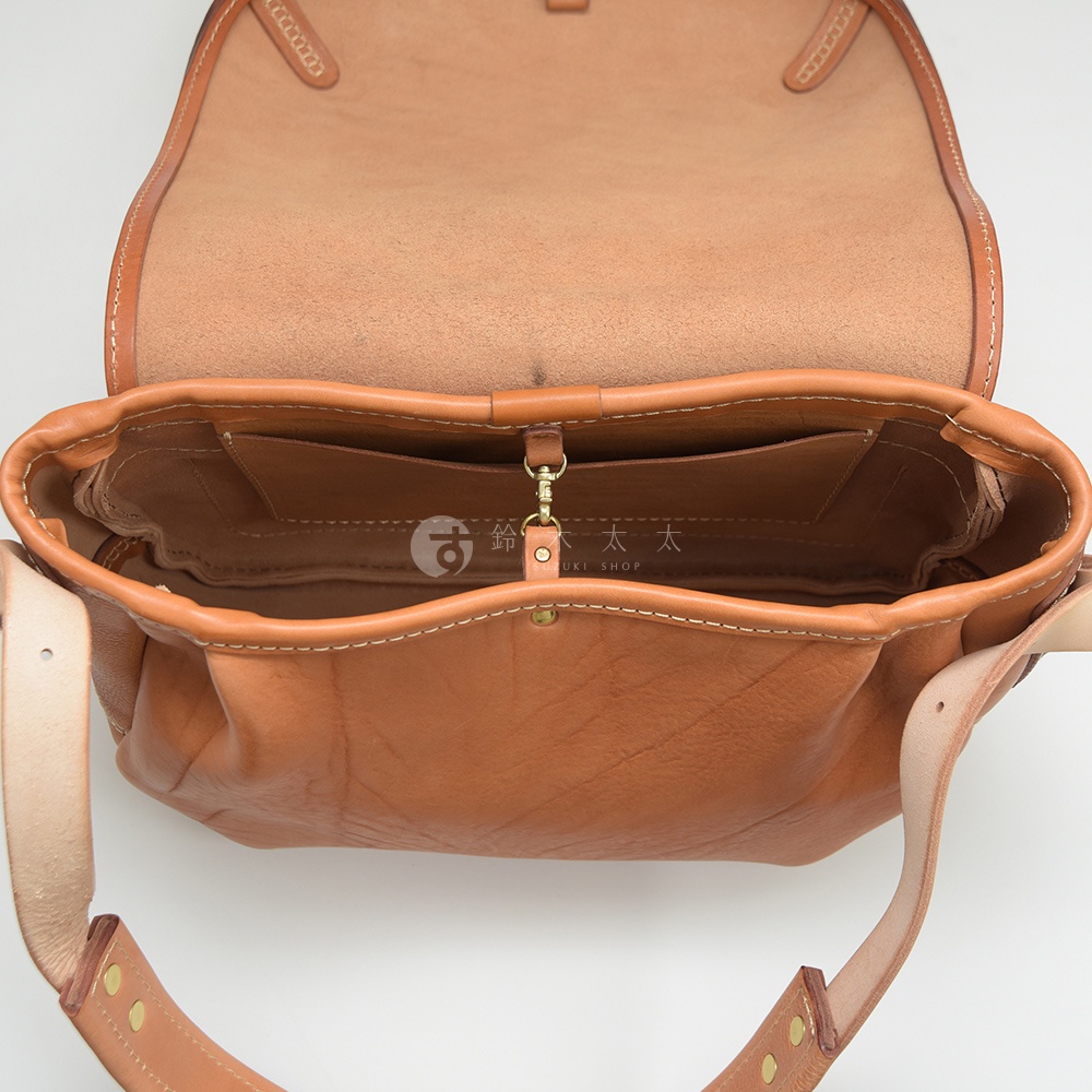 職人手作皮革大容量扣環郵差包，展示其內部結構，由淺棕色皮革製成，縫線清晰，配有金屬扣環及肩帶。
