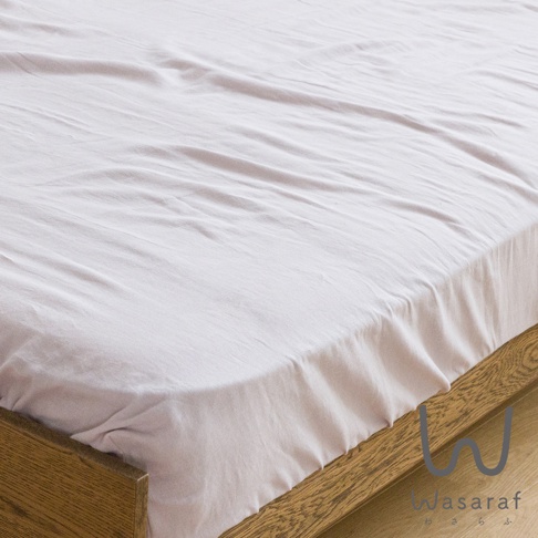 淡粉色雙人床包，材質為二層紗，蓋在木製床架上，布料有細緻的皺褶。