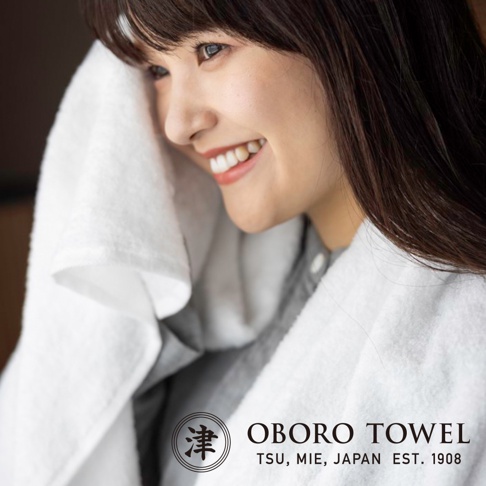 一位女子用白色柔軟毛巾擦拭臉部，毛巾材質蓬鬆，能有效吸水。