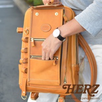 一款棕褐色皮革製成的兩用後背包，具有多個拉鍊口袋和皮製掛環。包包上有品牌標誌。