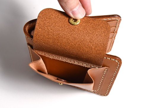 職人手作雙折短夾，材質為棕色牛皮，內附零錢袋，有金色按釦，縫線細緻。