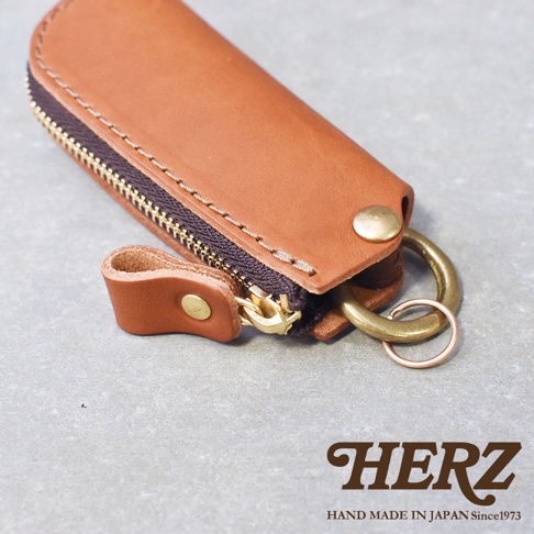 職人手作皮革Organ拉鍊鑰匙包，採用棕色皮革，搭配黃銅色拉鍊、釦子和鑰匙圈，設計簡約實用。