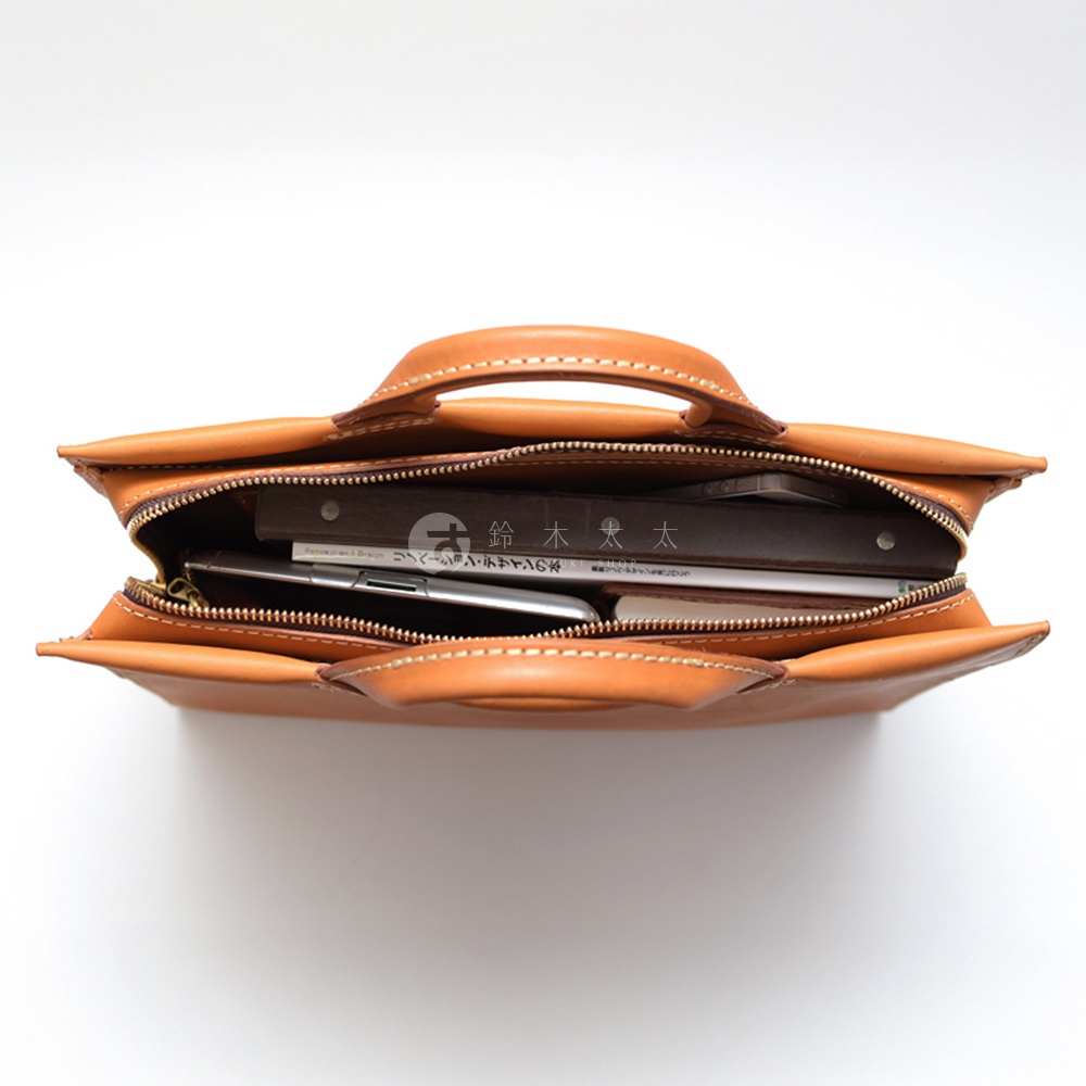 模式B： 皮革公事包打開，內有書本和手機，整體為焦糖棕色，俯視角度拍攝。