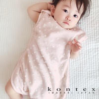 粉色紗布材質的嬰兒防踢被，表面帶有細緻白色小點綴，無袖設計，躺在白色格紋床墊上，左下角有「kontex IMABARI JAPAN」字樣。