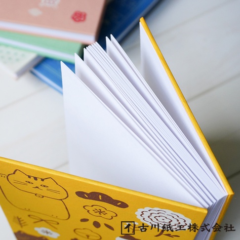 一本黃色封面的美濃和紙御朱印帳，封面印有可愛的貓咪圖案、雲朵和花朵，內頁為白色紙張，書頁展開。