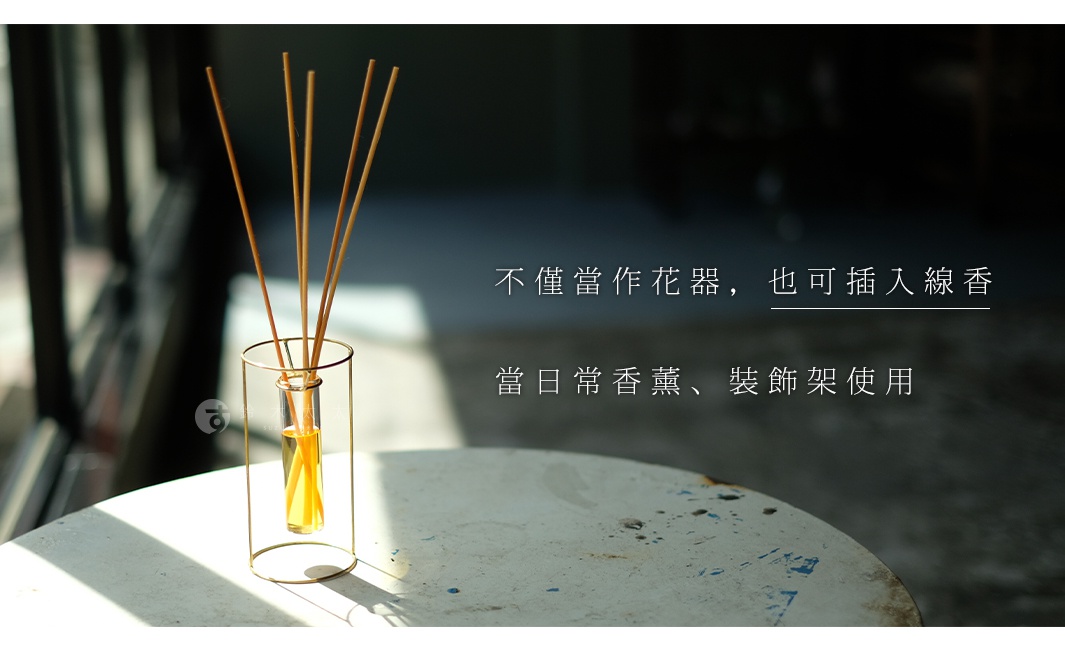 黃銅圓柱形支架內嵌試管花器，試管中盛有淡黃色液體，有數支細長的木質香薰棒插入其中。