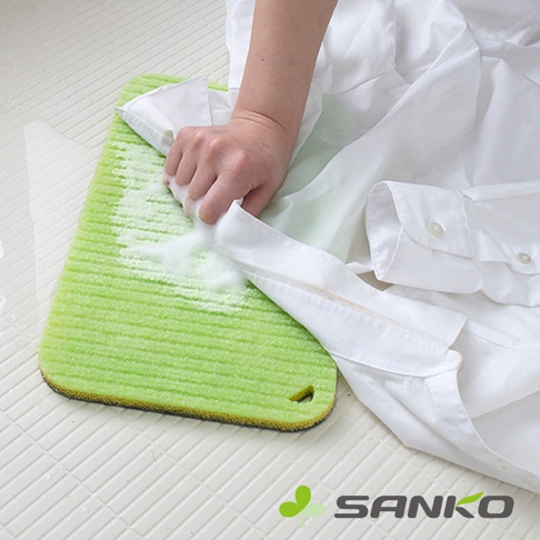 綠色網紋海綿洗衣板，搭配白色襯衫，一隻手正在搓洗領口污漬，產生白色泡沫。