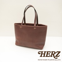 職人手作皮革4口袋極簡托特包 T-3，採用無內襯設計，呈現自然的皮革紋理，咖啡棕色，配有兩條皮革提把，包身有兩個金色鉚釘裝飾。