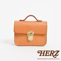 職人手作皮革迷你收納包 KF-14，採用天然皮革材質，呈現溫潤的淺棕色調，包款設有提把與黃銅色金屬鎖扣，縫線清晰，風格簡約復古。