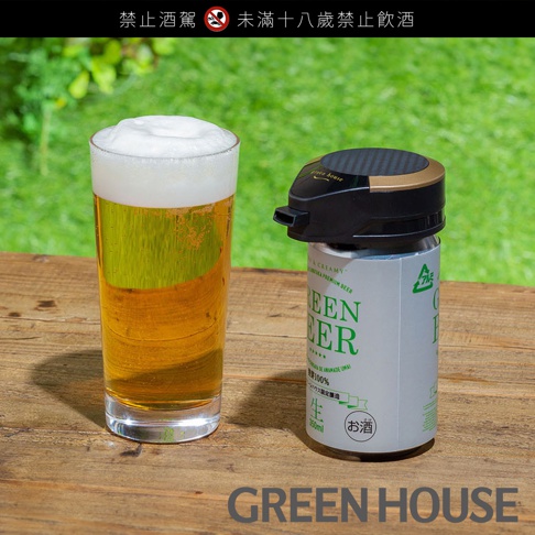 玻璃杯中裝有滿溢泡沫的淡黃色啤酒，旁邊擺放著一個銀色啤酒罐，罐上印有綠色文字「GREEN BEER」。啤酒罐上方裝有一個黑色和金色的蓋子，蓋子上有「green house」字樣。