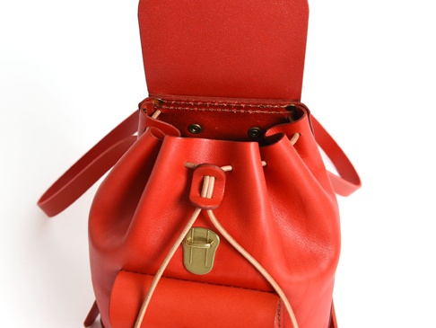 紅色皮革迷你後背包，抽繩束口設計，配有金色金屬扣和皮革肩帶。