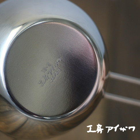 不鏽鋼長柄量杯，底部刻有「18-8 工房アイザワ JAPAN」字樣，銀色金屬材質，長柄設計。