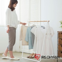 白色金屬框架的原木造型天然曬衣架，掛有淺米色、淺藍色、灰色和白色衣物，下方有兩雙高跟鞋。