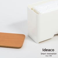 白色塑膠口罩收納抽取盒，內含疊放的白色口罩，旁邊擺放一個淺木色方形木蓋。