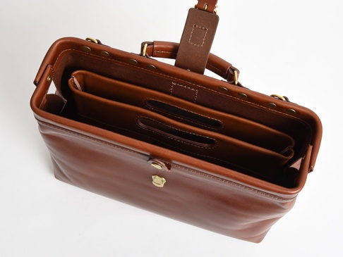 職人手作皮革橫式收納袋中袋，採用溫潤的咖啡棕色皮革製成，設有雙層內袋，外部有金屬釦環與提把，整體呈現經典復古風格。