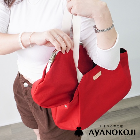 一位女子手提紅色口金托特包，展示其設計細節。