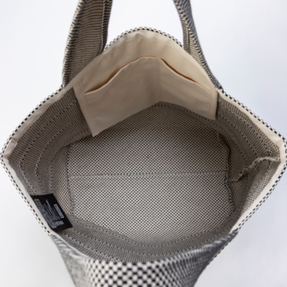 展示一款內部為米色內襯、外部為黑白格紋刺子織圖案的三河木綿大容量托特包。包內有兩個米色內袋。