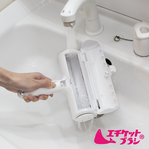 白色可水洗免耗材抗汙清潔滾輪，置於白色水槽中，在水龍頭下沖洗，手持滾輪清潔。