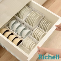 抽屜式餐盤收納架內，整齊擺放著不同尺寸的白色盤子和淺黃色碗，盤子垂直插入白色隔架中，碗則堆疊收納。