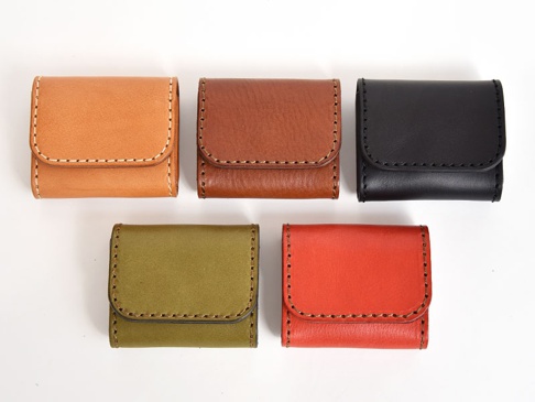 五個職人手作皮革雙折收納零錢包，分別為淺棕色、棕色、黑色、橄欖綠色和橘紅色，皆為皮革材質，以白色縫線裝飾邊緣。