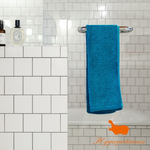 藍色竹棉混紡長毛巾，厚實柔軟，掛於浴室毛巾架上，背景為白色瓷磚牆。