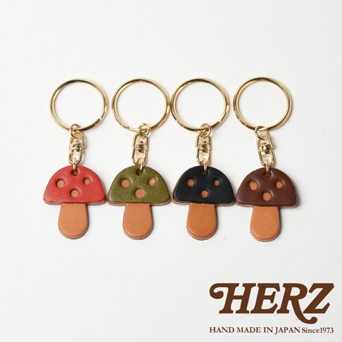 四款職人手作皮革香菇造型鑰匙圈，分別為紅色、墨綠色、黑色與棕色，皆使用皮革製作，搭配金色鑰匙圈。