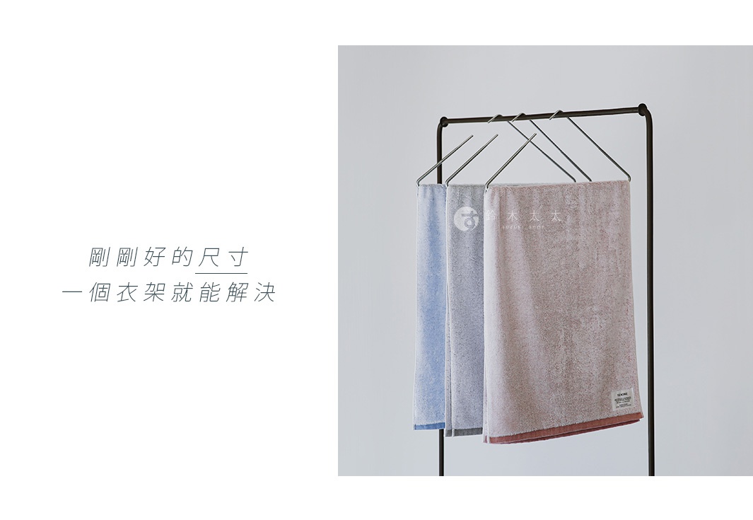 YUKINE 雪中漫步有機棉蓬厚毛巾，展示了三條不同顏色的毛巾：淺藍色、灰色和粉紅色，懸掛在黑色衣架上，材質蓬鬆柔軟。