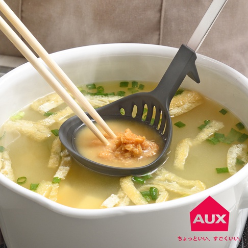 AUX 品牌 logo 下方有日文文字，湯匙裡裝有味噌湯料，由筷子夾起，湯匙置於一鍋味噌湯中。