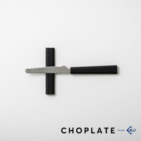 CHOPLATE KNIFE 兩用砧板盤專用刀，具有銀色鋸齒刀刃和黑色手柄，刀刃置於黑色砧板盤上，呈現十字形狀。